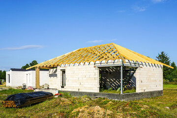 Fototapeta na wymiar Unfinished residential house with white concrete block walls and a wooden beam truss roof structure