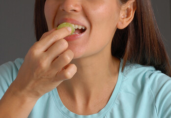 Young woman eating green grapes fruit portrait.