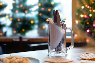 Cutlery and white napkins in a beer mug on a table in a street cafe against the background of...