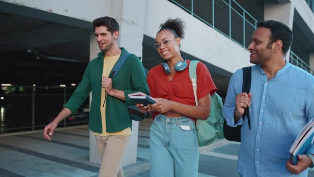 Happy multicultural students talking and walking with backpacks outdoors 