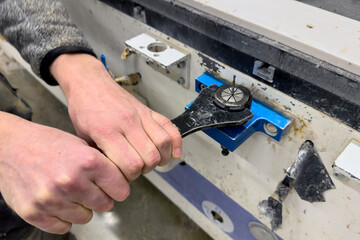 A CNC machine operator changes a cutter. Close-up of the hands of a CNC machine operator using a...