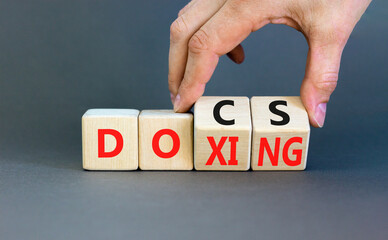 Docs or doxing symbol. Concept words Docs Doxing on wooden block. Beautiful grey table grey background. Businessman hand. Business docs or doxing concept. Copy space.