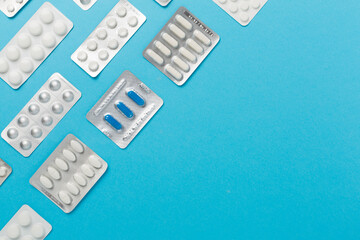 Pills in different packaging on color background, top view