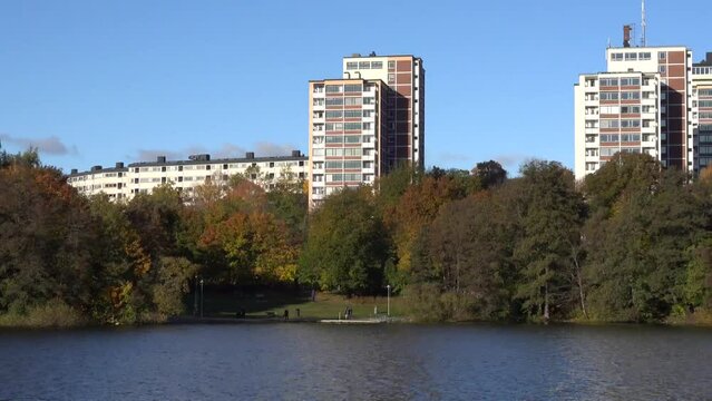 Stockholm, Sweden A panning view of high-rise apartment buildings in the Grondal district and the Trekanten Lake in the autumn colors. 