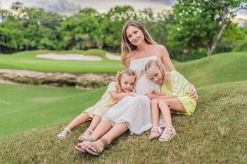 Fototapeta premium A happy family, two girls, dad, and a pregnant mom, enjoys quality time together on a lush green lawn, creating cherished memories of togetherness