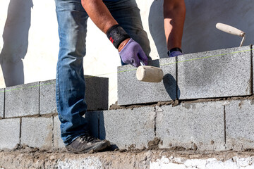 A builder lays an aerated concrete block on a wall