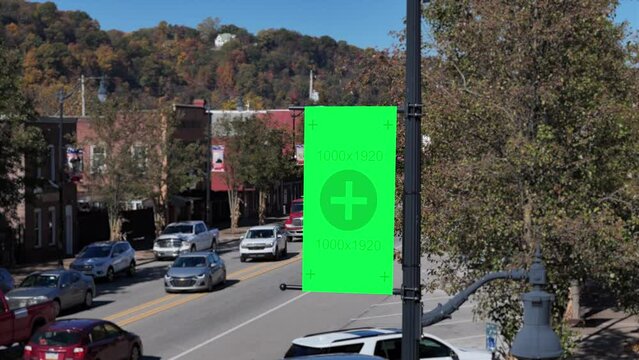 An aerial closeup view of a green screen banner on a lamp post in a small American town. Pittsburgh suburbs.  	