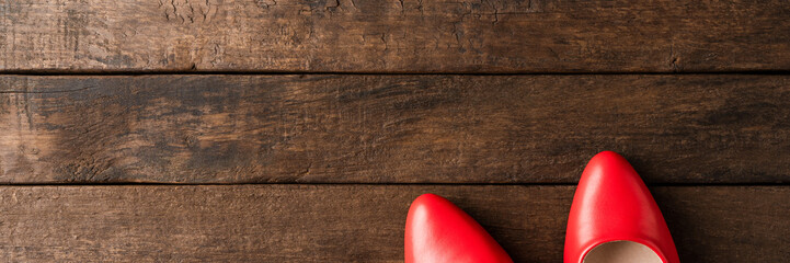 Red high heels on wooden background with copyspace. Women’s shoes - obrazy, fototapety, plakaty