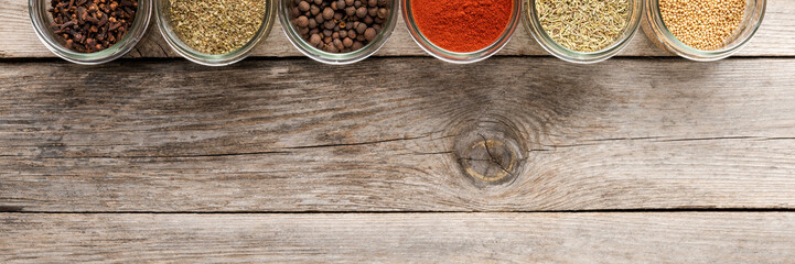 Mix of colourful spices in bowls on wooden table with copyspace. Collection of seasonings. Top view
