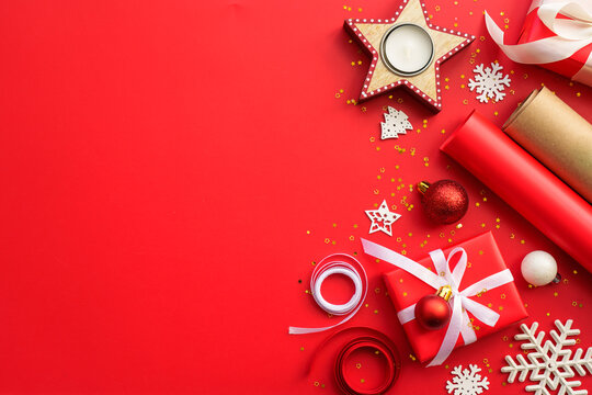 Christmas Present box and decorations at red background. Wrapping christmas present. Flat lay image with copy space.
