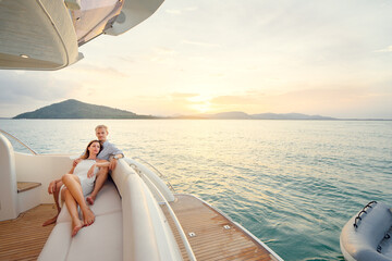 Romantic vacation and luxury travel. Young loving couple sitting on the sofa on the modern yacht...