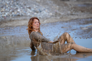 A woman expresses her emotions in a muddy puddle