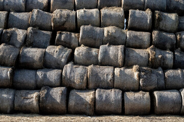 Hay in stacks on the field. View of hay in rolls. Rolls of straw are folded into a pyramid. Stocks of dry grass for the winter. Pet food for the winter.
