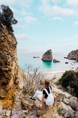 Tourism concept. Young traveling woman with rucksack enjoying ocean view.