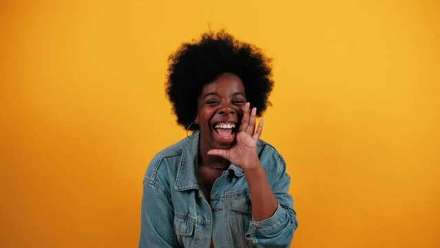 Young African American woman screaming WOW, surprise, shocked, expresses gestures. Pretty girl isolated on yellow studio background indoors