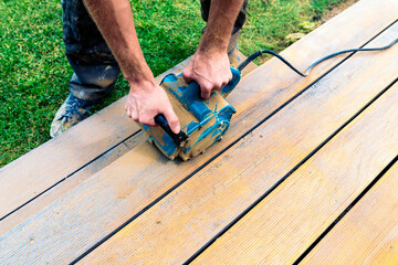 Machine cleaning of a wooden terrace - dry method - grinding the boards with handy sanding machine, preparing for oiling the terrace