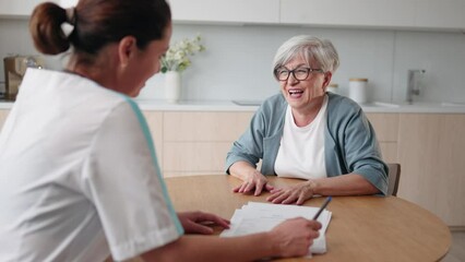 Senior woman patient complaining headache migraine sitting on kitchen at home. Empathic female doctor medical practitioner therapist filling disease history form, provide help prescribe treatment.