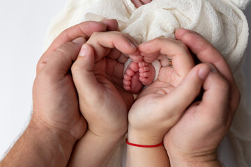 Feet of a newborn baby in the arms of the parents. legs of a newborn baby in his hands. baby's legs. baby feet in the background