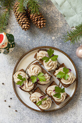 Creative appetizer christmas. Creamy pate sandwiches of herring on a rye bread on the festive table. View from above.