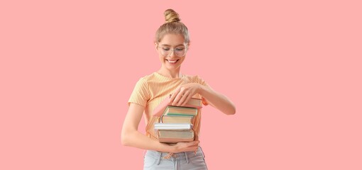Young woman with stack of books on pink background