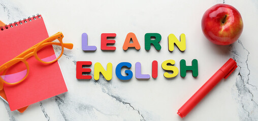 Text LEARN ENGLISH, apple and stationery on light background