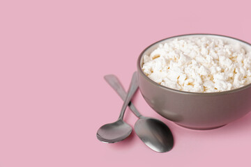 Bowl with tasty cottage cheese on pink background