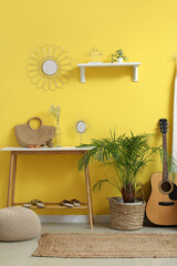 Interior of stylish hallway with mirror, console table, guitar and houseplant