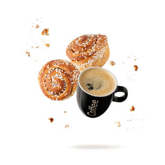 Black cup hot espresso coffee and fresh baked cinnamon buns with crumbs and sugar pieces flying...