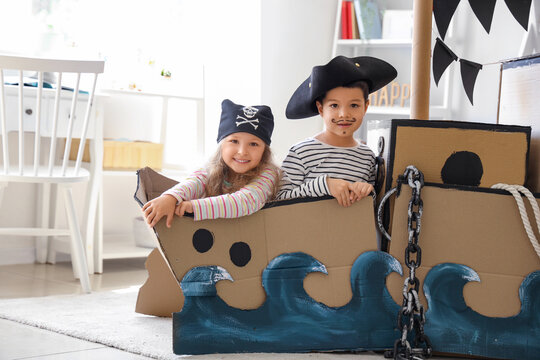 Cute little pirates playing in cardboard ship at home