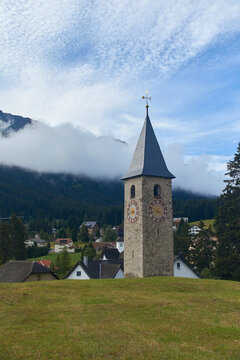 Beautiful swiss alpine countryside with a medieval bell tower with a clock and Rothorn mountain on background in Churwalden village in Switzerland formerly Parpan