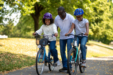 African american family having good time in a park and riding bikes