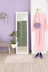 Interior of stylish hallway with mirror and dress hanging on hangers