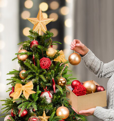 woman's hand hanging a Christmas ornament on a Christmas tree