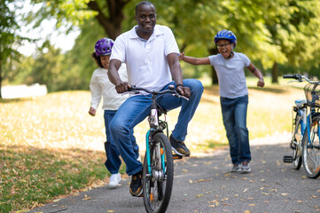 Happy family riding a bike in a park and having fun together
