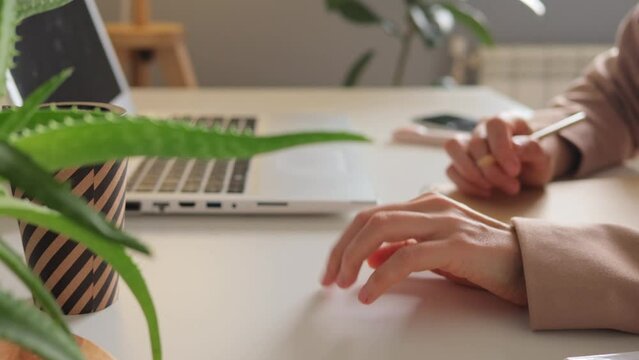 Anxiety, stress, boredom, impatience and nervousness related to work. Unrecognizable woman's hand that anxiously taps her desk with her fingers while working on laptop at office.