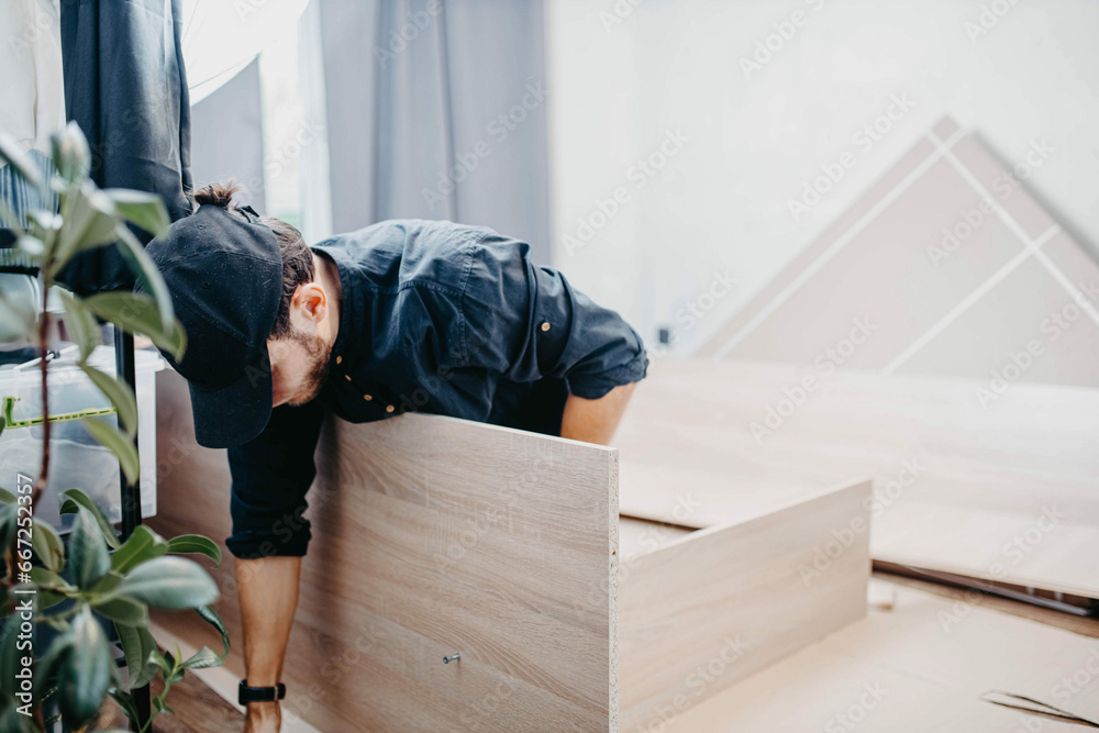 Wall mural man assembling furniture wooden cabinet at home