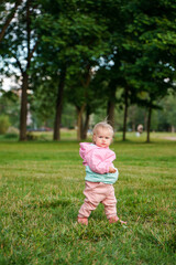 Cute caucasian kid baby sitting on the grass in a jacket