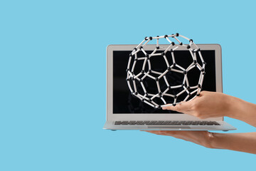 Woman with laptop and molecular model on blue background