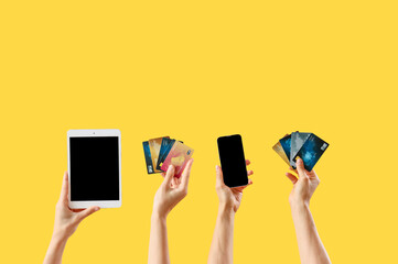 Women with gadgets and credit cards on yellow background
