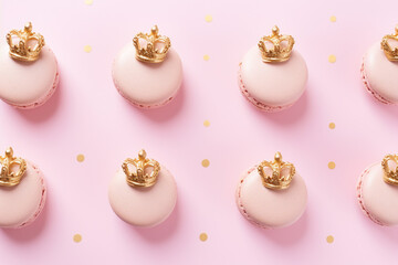 Princess themed birthday: delicate pastel pink macarons decorated with a golden crown pattern on a pink background