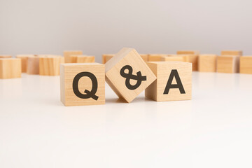 three wooden cubes with Q and A symbols on them. white background. in the background there are many wooden blocks of different sizes