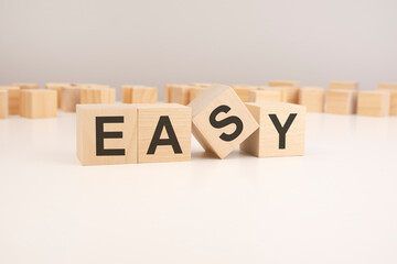 selective focus. word EASY is written on a wooden cubes structure. blocks on a bright background. can be used for business and financial concept.