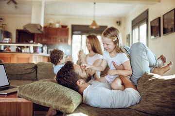 Loving young family playing on the couch together at home