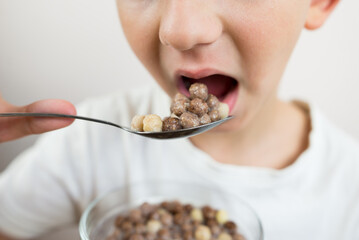 cropped photo of a boy eating breakfast cereal in the form of milk balls.
