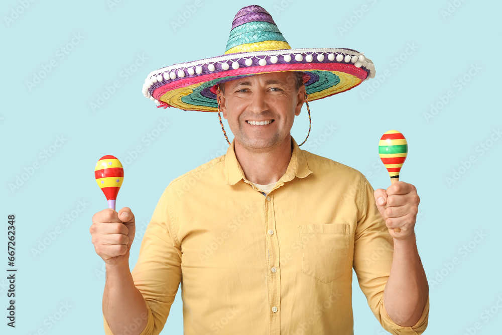 Sticker Handsome mature Mexican man in sombrero hat with maracas on blue background