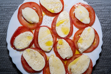 Tomato mozzarella with olive oil on a white plate 