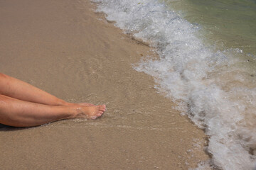 Beautiful view of woman's legs being caressed by waves of Atlantic Ocean on sandy shores of Miami Beach.