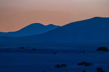 View of the dunes of Corralejo and silhouetted hills at sunset on the Canary Island of Fuerteventura, Spain.