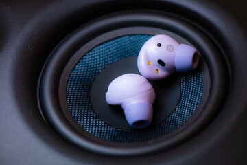 wireless earpone buds on speakers background