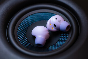 wireless earpone buds on speakers background